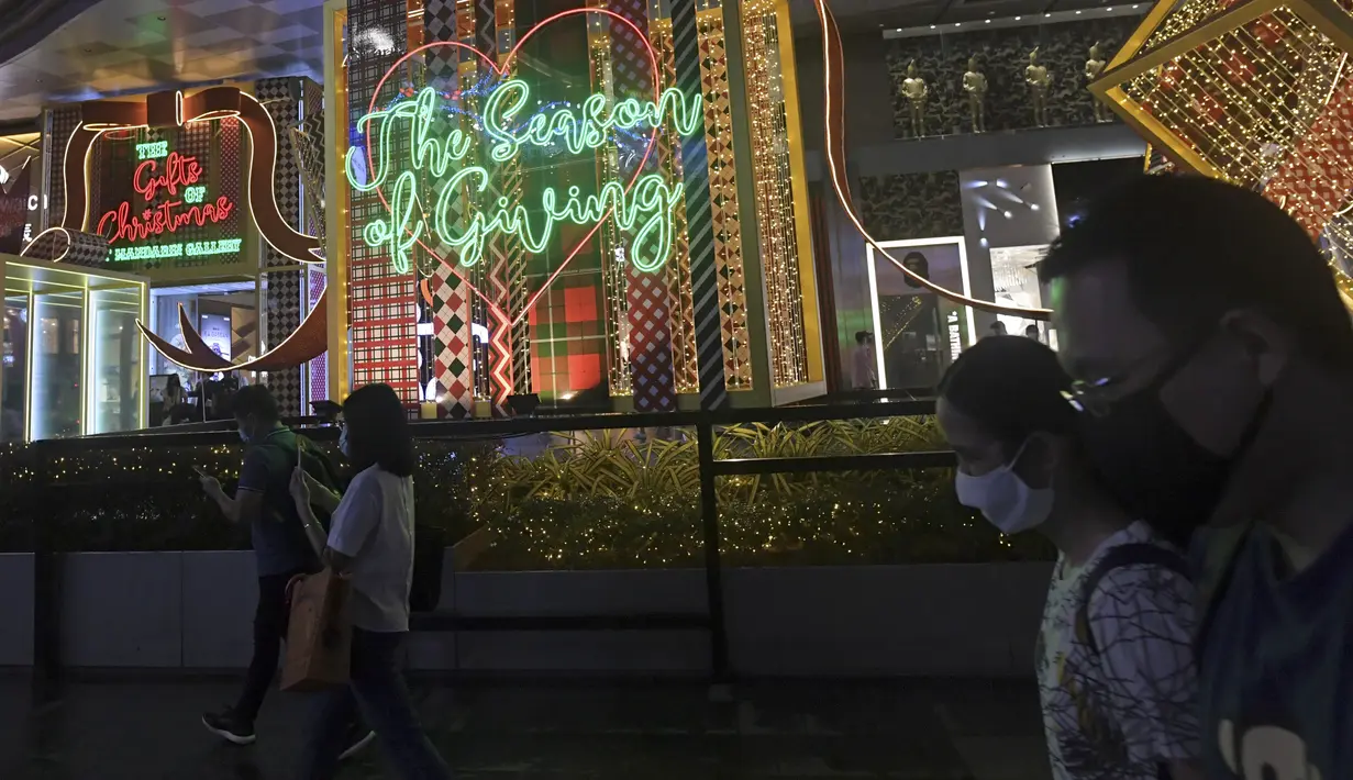 Orang-orang berjalan melewati dekorasi lampu Natal di luar pusat perbelanjaan di sepanjang kawasan Orchard road di Singapura, Selasa (8/12/2020). Mengusung tema Love This Christmas, acara tahun ini lebih sunyi karena aktivitas jalanan dibatasi di tengah pandemi Covid-19. (ROSLAN RAHMAN / AFP)