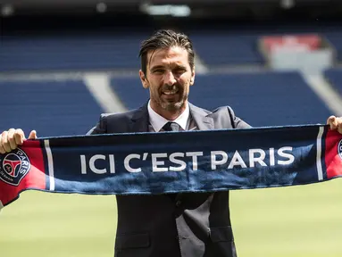 Kiper anyar PSG, Gianluigi Buffon berpose dengan syal klub barunya saat sesi perkenalan di stadion Parc des Princes, Paris, Senin (9/7). Paris Saint-Germain ( PSG) secara resmi memperkenalkan Gianluigi Buffon sebagai pemain baru. (AP/Jean-Francois Badias)