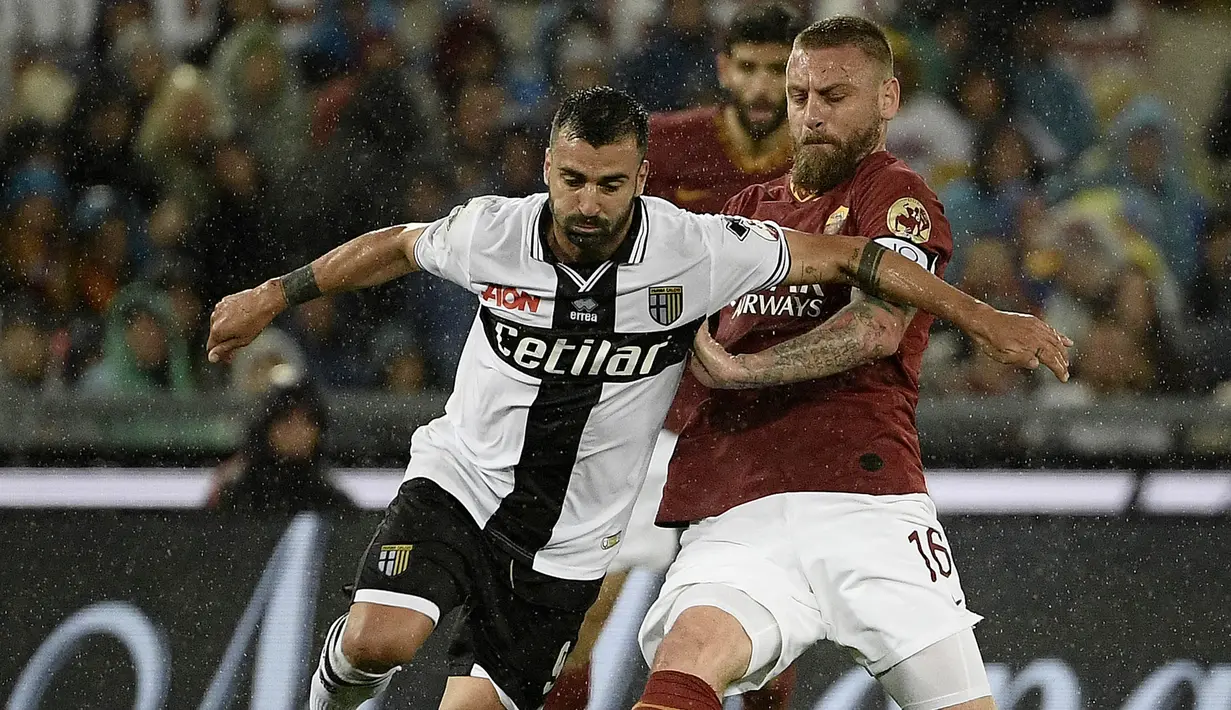 Gelandang AS Roma, Daniele De Rossi, berebut bola dengan striker Parma, Fabio Ceravolo, pada laga Serie A di Stadion Olympic, Roma, Minggu (26/5). Laga ini perpisahan bagi De Rossi dan AS Roma setelah 18 tahun. (AFP/Filippo Monteforte)
