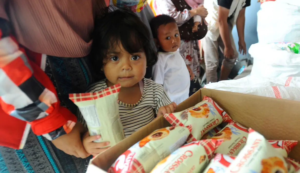 Warga antre mendapatkan pampers dan biskuit bagi anak-anak di Posko pengungsian Mangunkerta, Cianjur, Jumat (23/12/2022). Lebih dari sebulan sejak musibah gempa bumi 5,2 SR sejumlah warga masih tinggal di pengungsian dengan bantuan kebutuhan hidup dari para donatur. (merdeka.com/Arie Basuki)