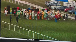 Penonton melihat layar yang menggambarkan peserta lomba lari Mascot Gold Cup bersiap memulai balapan di Wetherby Racecourse, Inggirs (29/4). (AFP/Oli Scarff)