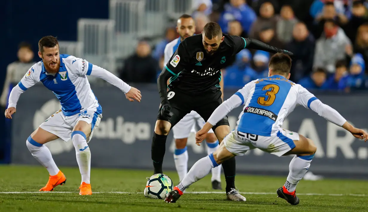 Pemain Real Madrid, Karim Benzema dan pemain Leganes, Unai Bustinza Leganes berebut bola pada partai tunda pekan ke-16 La Liga Spanyol di Estadio Municipal de Butarque, Rabu (21/2). Real Madrid bangkit dari ketinggalan dengan skor 3-1. (AP/Francisco Seco)