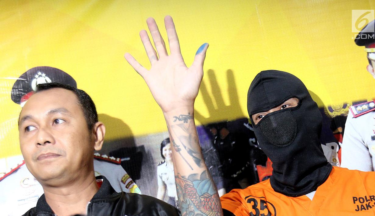 Aktor Tora Sudiro (kenakan penutup wajah hitam) melambaikan tangan dalam jumpa pers kepemilikan psikotropika di Mapolres Jakarta Selatan, Jumat (04/08). Tora terancam penjara maksimal 5 tahun. (Liputan6.com/Herman Zakharia)