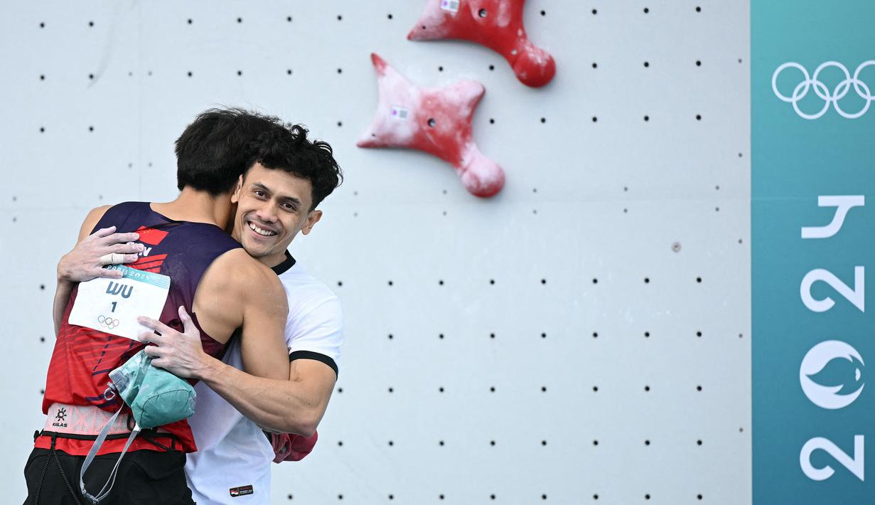 Atlet panjat tebing Indonesia, Veddriq Leonardo (kanan) berpelukan dengan wakil China, Wu Peng setelah memastikan kemenangan pada cabang olahraga pajat tebing nomor speed Olimpiade Paris 2024 di Le Bourget Sport Climbing Venue, Paris, Prancis, Kamis (08/08/2024). (AFP/Jonathan Nackstrand)