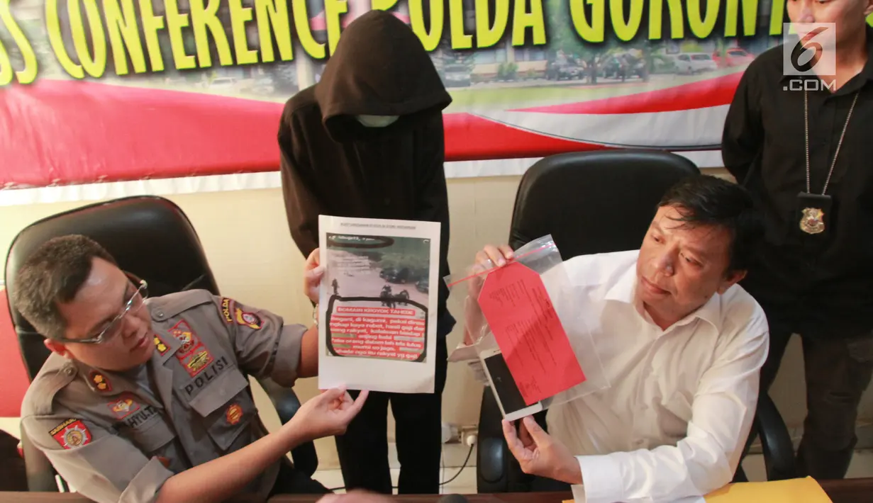 Petugas menunjukkan barang bukti beserta pria IB alias Ismail di Polda Gorontalo, Selasa (28/5/2019). IB harus berurusan dengan pihak kepolisian setelah ia memposting salah satu video kekerasan yang sudah ditambah bahwa itu merupakan kekerasan yang dilakukan Kepolisian.(Liputan6.com/Arfandi Ibrahim)