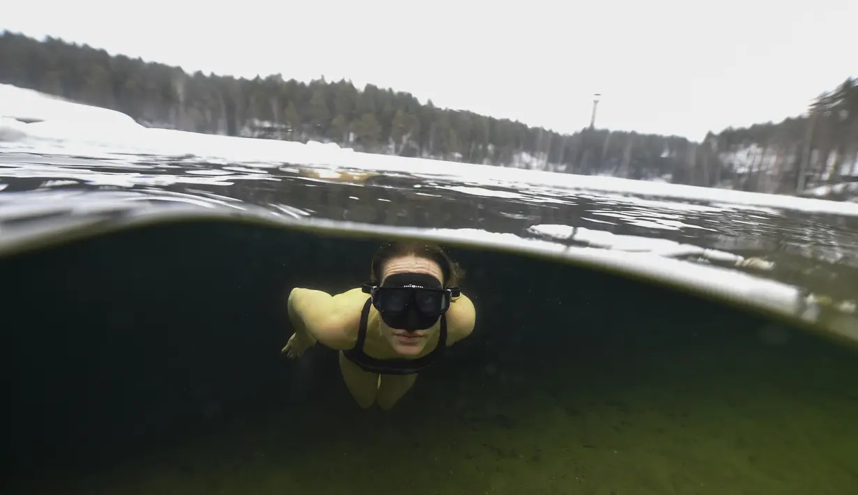 Johanna Nordblad menyelam di danau beku, Somero, Finlandia, Selasa (27/2). Johanna Nordblad memegang rekor dunia freediving di bawah es dengan baju renang sejauh 50m. (AFP PHOTO / Olivier Morin)