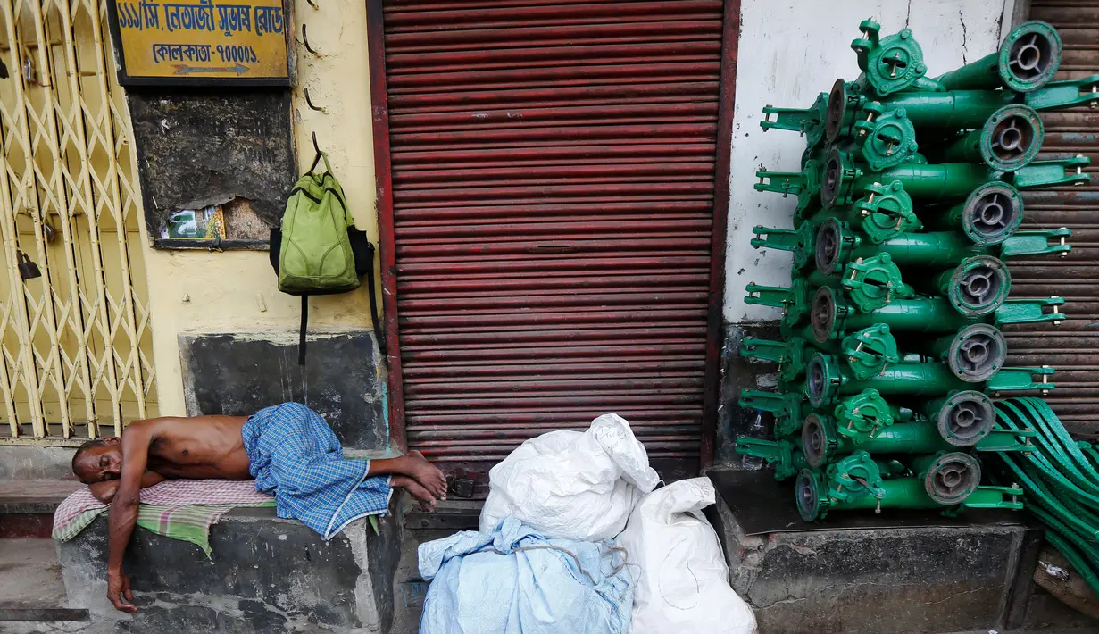 Pekerja tidur di samping pompa tangan besi di pasar grosir besi di Kolkata, India (26/5/2016). Transportasi publik yang ada di kota Kalkuta ialah Suburban Railway, Kolkata Metro, tram, dan bus. (REUTERS/Rupak De Chowdhuri)