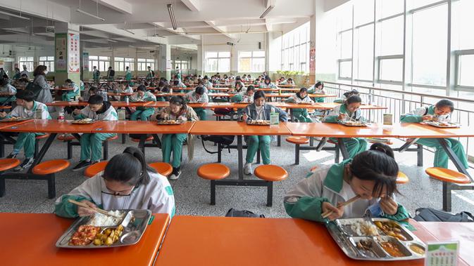 Para siswa makan siang di Sekolah Menengah Atas No.9 Yinchuan di Yinchuan, Daerah Otonom Etnis Hui Ningxia, China barat laut, Rabu (25/3/2020). Para siswa tahun terakhir sekolah menengah pertama dan sekolah menengah atas di Yinchuan kembali masuk sekolah. (Xinhua/Yang Zhisen)