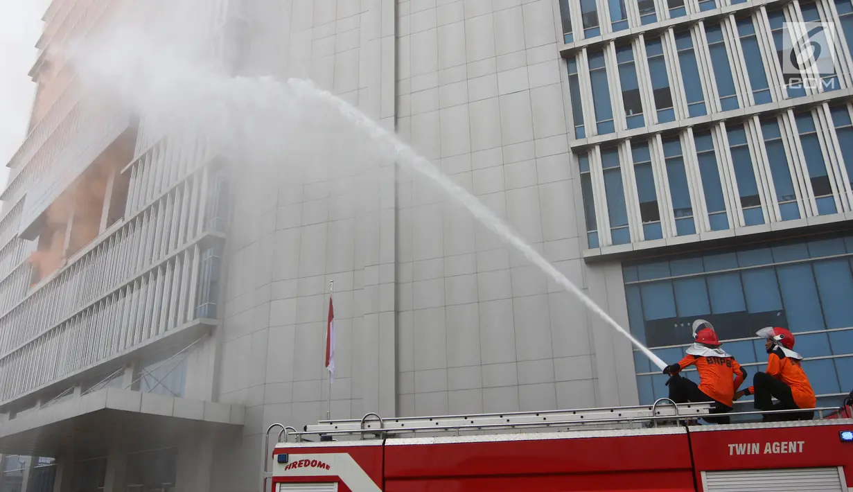 Pemadam kebakaran menyemprotkan air ke dalam gedung saat simulasi bencana di Gedung Graha BNPB, Jakarta, Kamis (26/4). (Liputan6.com/Arya Manggala)