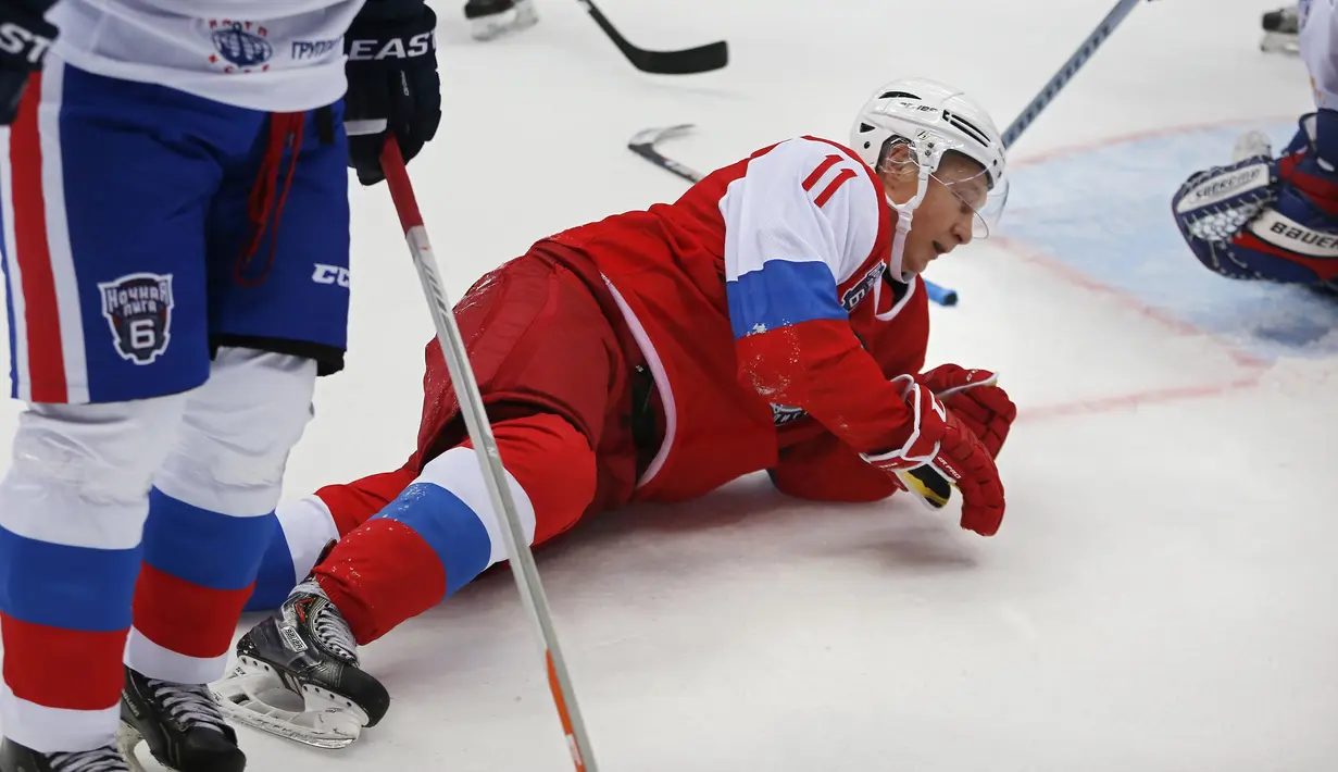 Presiden Rusia, Vladimir Putin terjatuh saat bermain hoki es dalam pertandingan persahabatan Night League di Sochi, Rusia, (10/5). Putin bermain bersama tim "Hockey Legends" dan berhasil menang 17-6. (AFP Photo/Pool/Yuri Kochetkov) 