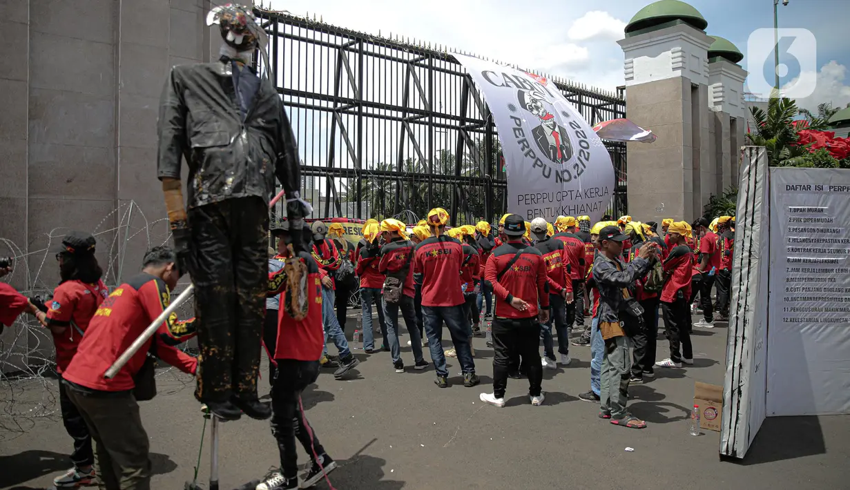 Elemen buruh menggelar aksi unjuk rasa di gedung DPR RI, Jakarta, Selasa (10/1/2023). Massa aksi yang menolak Perppu Cipta Kerja tersebut terlihat membawa bendera berwarna merah memenuhi halaman depan gedung DPR. (Liputan6.com/Faizal Fanani)