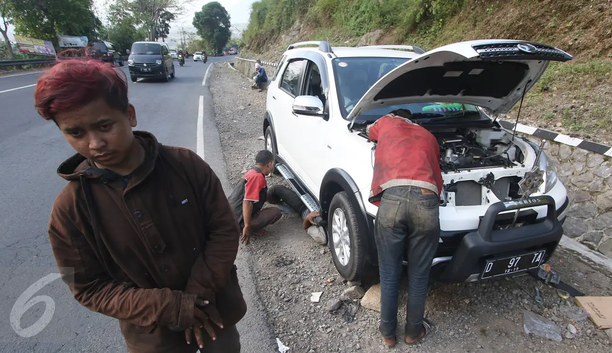 Montir memperbaiki mobil yang rusak di Jalan Warung Peuteuy, Garut, Jabar, Senin (4/7). Banyaknya kendaraan pemudik yang rusak menjadi berkah bagi para montir panggilan dengan pendapatan hingga 4x lipat dibanding biasa. (Liputan6.com/Immanuel Antonius)