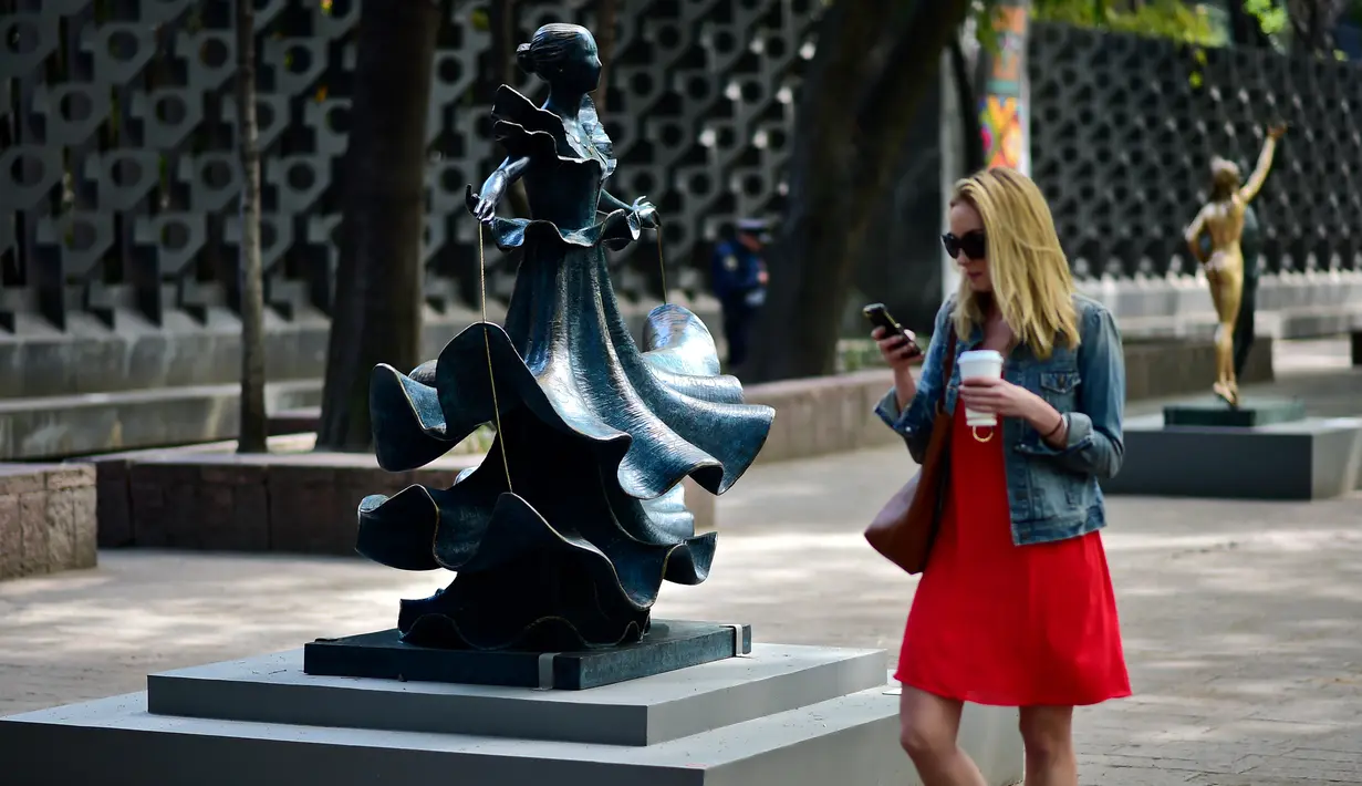 Seorang wanita melintas di dekat patung "Dalinian Dancer" saat pameran "Salvador Dali: Urban Dreams" di Mexico City, Selasa (14/3). Patung-patung tersebut adalah karya seniman asal spanyol yang bernama Salvador Dali. (AFP PHOTO / RONALDO SCHEMIDT)