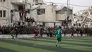Seketika, aura kehidupan kembali bergelora melupakan luka perang yang masih terasa. Tampak dalam foto, warga Palestina menyaksikan pertandingan sepak bola lima lawan lima di tengah reruntuhan bangunan yang hancur di Kota Gaza pada Senin 9 Februari 2026. (Omar AL-QATTAA/AFP)