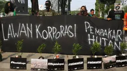 Aktivis Wahana Lingkungan Hidup Indonesia (Walhi) memperlihatkan spanduk saat melakukan aksi protes pembakaran hutan di Jakarta, Selasa (8/8). (Liputan6.com/Immanuel Antonius)