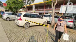 Seorang perempuan melintas di antara mobil yang parkir di Rest Area Km 13,5 di Tol Tangerang, Selasa (19/5/2020). Jelang Lebaran, PT Jasamarga Related Business menerapkan PSBB di semua rest area yang dikelolanya dengan membatasi waktu singgah pengunjung maksimal 30 menit. (Liputan6.com/Angga Yuniar)
