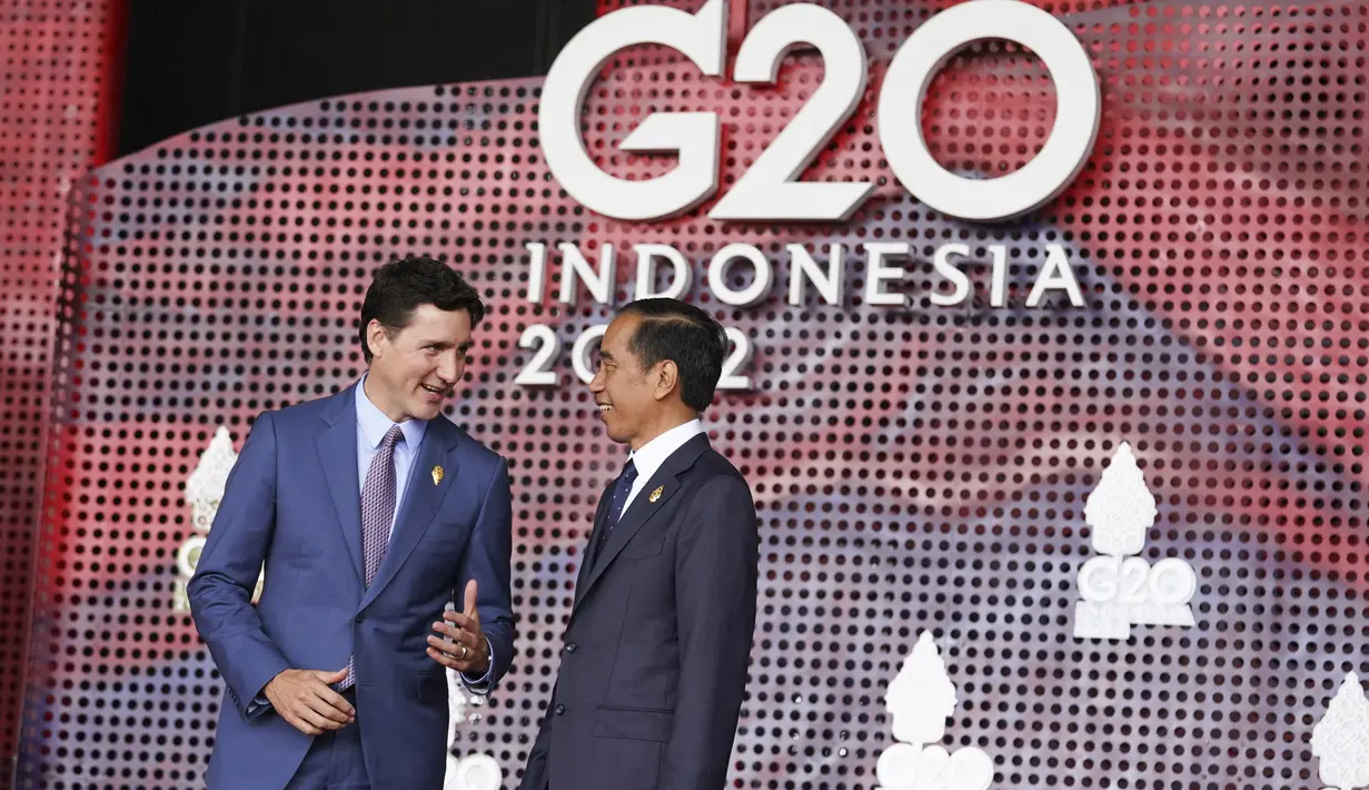 Perdana Menteri Kanada Justin Trudeau berbicara dengan Presiden Indonesia Joko Widodo atau Jokowi yang menyambutnya pada hari pertama Konferensi Tingkat Tinggi (KTT) G20 di Nusa Dua, Bali, Selasa (15/11/2022) pagi. Jokowi menyampaikan ucapan selamat datang di lobi depan venue utama KTT G20. (KEVIN LAMARQUE / POOL / AFP)