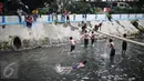 Anak-anak berenang dan bermain air di aliran Kali Gresik di Jalan Muhammad Yamin, Menteng, Jakarta, Minggu (26/2). (Liputan6.com/Faizal Fanani)