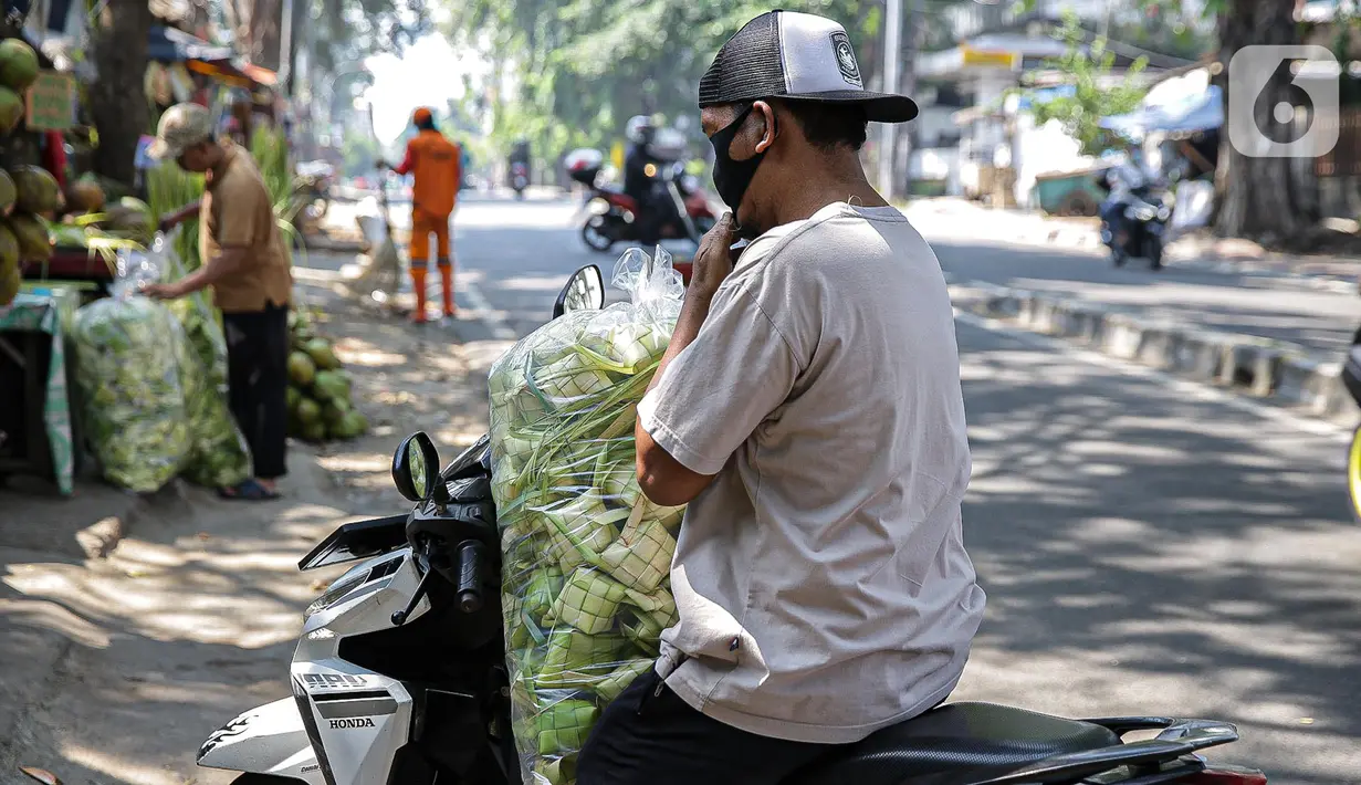 Pembeli membawa cangkang ketupat menggunakan sepeda motor di kawasan Palmerah, Jakarta, Minggu (18/7/2021). Pemberlakuan PPKM Darurat membuat penjualan cangkang ketupat jelang Idul Adha tahun ini sepi pembeli. (Liputan6.com/Faizal Fanani)