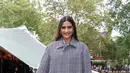 Aktris Sonam Kapoor tampil chic mengenakan checkered print midi dress abu-abu dipadukan trench coat matching dan leggings. [Dok/Burberry]
