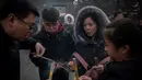 Keluarga membakar dupa untuk berdoa keberuntungan pada hari kelima Tahun Baru Imlek di Yonghegong, atau Kuil Lama di Beijing (9/2). Warga China merayakan Tahun Babi tersebut dengan doa, pesta keluarga, dan belanja. (AFP Photo/Nicolas Asfouri)