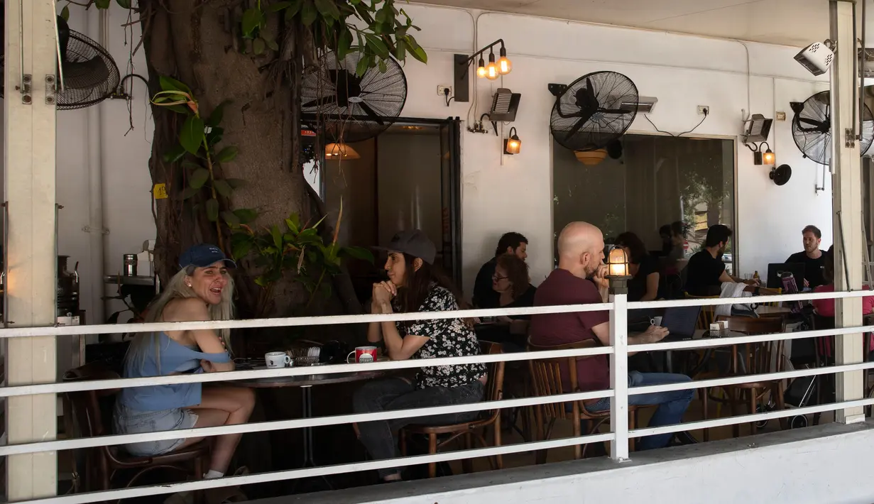 Pengunjung makan di luar di sebuah restoran di Tel Aviv, Israel pada Rabu (27/5/2020). Setelah lebih dari dua bulan ditutup untuk membendung penularan virus corona, restoran hingga kafe di Israel diizinkan dibuka kembali hari Rabu, 27 Mei. (AP Photo/Sebastian Scheiner)