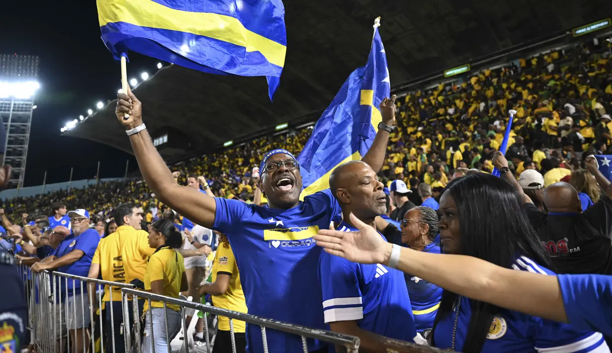 Hasil imbang tersebut mengukuhkan performa konsisten Curacao di Grup B Kualifikasi Piala Dunia 2026 zona CONCACAF yang sebelumnya mencatat tiga kemenangan dan tiga hasil imbang tanpa kekalahan. Tampak dalam foto, suporter Timnas Curacao merayakan hasil imbang melawan Jamaika pada Grup B Kualifikasi Piala Dunia 2026 zona CONCACAF di Independence Park Stadium, Jamaika pada 18 November 2025. (Ricardo MAKYN/AFP)