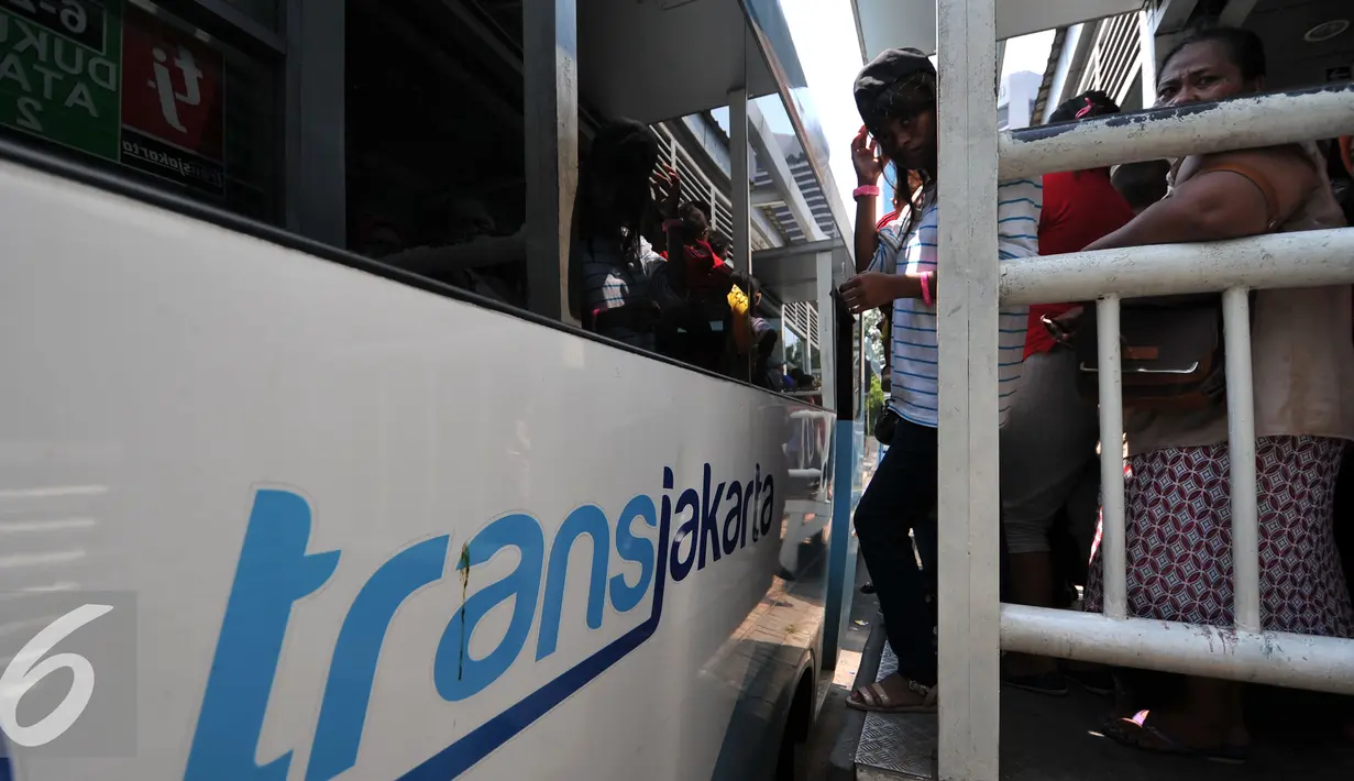 Penumpang berdesakan saat menaiki bus Transjakarta menuju Ragunan di Halte Dukuh Atas 2, Jakarta, Jumat (1/1/2016). Ratusan penumpang menumpuk menunggu bus TransJakarta tujuan Ragunan untuk menikmati libur panjang 2016. (Liputan6.com/Yoppy Renato)