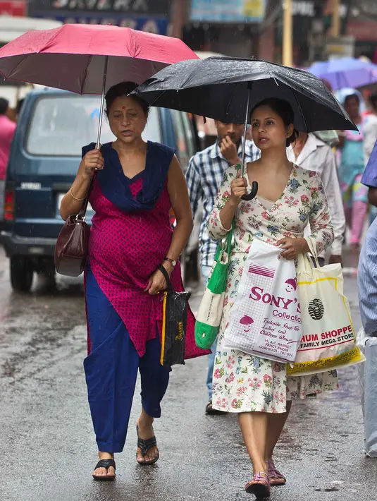 Dua orang wanita berjalan sambil menggunakan payung saat hujan mengguyur kota Gauhati, India, Selasa (30/5). Beberapa negara bagian di India timur laut mengalami hujan deras sebagai efek topan Mora yang melanda selatan Bangladesh. (AP Photo/ Anupam Nath)