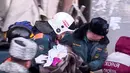 Tim penyelamat menggendong bayi yang ditemukan tertimbun reruntuhan gedung apartemen yang ambruk di Magnitogorsk, Rusia, Selasa (1/1). Bayi itu segera dibungkus selimut dan dievakuasi ke rumah sakit. (Russian Ministry for Emergency Situations via AP)