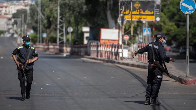 Polisi Hamas Palestina mengenakan masker berjaga di sebuah jalan saat pemberlakukan lockdown total selama 48 jam di Jalur Gaza, Selasa (25/8/2020). Lockdown dan jam malam diberlakukan menyusul terkonfirmasinya kasus Covid-19 pertama kalinya di sebuah kamp pengungsian. (AP Photo/Khalil Hamra)
