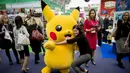 Seorang pengunjung berpose dengan karakter kartun Pikachu dari Pokemon saat Toy Fair atau Pameran Mainan tahunan di Olympia, London, Inggris, Selasa (23/1). Pameran ini menghadirkan lebih dari 250 perusahaan mainan. (AFP PHOTO/Tolga AKMEN)
