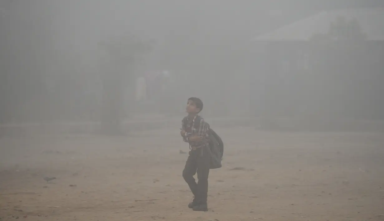 Seorang anak sekolah India melewati jalan di New Delhi yang diselimuti kabut asap, Rabu (8/11). Kabut asap tebal akibat polusi udara yang parah menyebabkan aktivitas di pusat kota New Delhi lumpuh seketika. (SAJJAD HUSSAIN/AFP)