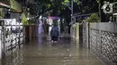 Warga berjalan menerjang banjir karena hujan di Jalan Shofa Marwah, Jakarta, Jumat (4/11/2022). Berdasarkan laporan Badan Penanggulangan Bencana Daerah (BPBD) DKI Jakarta yang diperbaharui pada pukul 18.00 WIB, terdapat 4 RT yang terendam banjir dengan ketinggian maksimal mencapai 50 Cm. (Liputan6.com/Faizal Fanani)