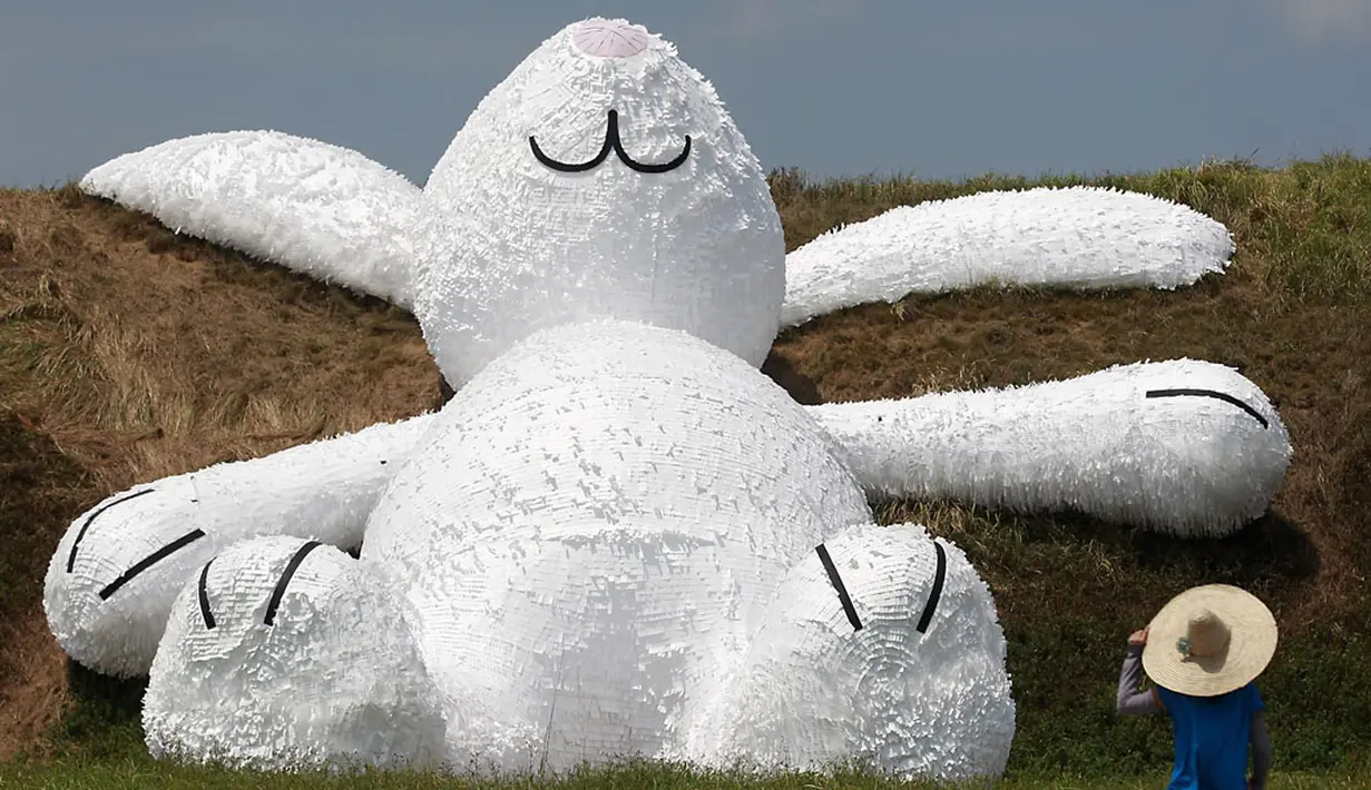 Salah satu pengunjung memperhatikan kelinci raksasa yang dipamerkan pada Taoyuan Land Art Festival di Taiwan, (3/9/2014). (REUTERS/Pichi Chuang)