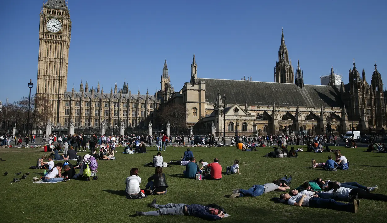 Sejumlah orang bersantai di bawah sinar matahari di Parliament Square di pusat kota London Inggris, Sabtu (8/4). (AFP PHOTO / Daniel Leal-Olivas)