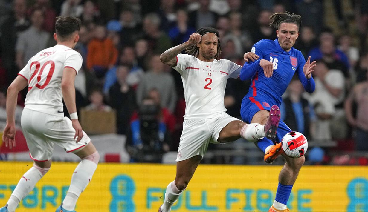 Pemain Swiss Kevin Mbabu (tengah) berebut bola dengan pemain Inggris Jack Grealish pada pertandingan uji coba di Stadion Wembley, London, Inggris, 26 Maret 2022. Inggris menang 2-1. (AP Photo/Alastair Grant)