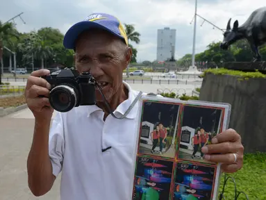 Fotografer taman, Joel Estrella berpose dengan kameranya di sebuah taman di Manila, Filipina (22/4). Estrella telah bekerja sebagai fotografer taman sejak tahun 1970. (AFP Photo/Ted Aljibe)