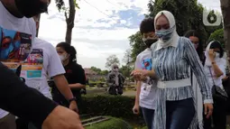 Mantan Anggota DPR Angelina Sondakh bersama kedua anaknya Aaliyah Massaid dan Keanu Jabbar Massaid saat ziarah makam di TPU Jeruk Purut, Jakarta Selatan, Kamis (3/3/2022). Kedatangan mereka untuk berziarah ke makam Adjie Massaid dan bapak dari Adjie Massaid. (Liputan6.com/Herman Zakharia)