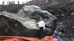Pejabat setempat, Tint Soe berpose di samping batu giok yang ditemukan penambang di lokasi tambang di negara bagian Kachin, Myanmar, Kamis (20/10). Bongkahan batu giok seberat 174 ton itu dilaporkan tidak bisa dipindahkan dari lokasi penemuan. (STR/AFP)