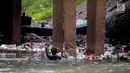 Aksi petugas PPSU bersihkan sampah yang tersangkut ditengah deras arus aliran anak kali Ciliwung, Jakarta, Senin (22/7/2019). Pembersihan sungai dari berbagai sampah tersebut dimaksudkan agar tidak ada penumpukan sampah dan sedimentasi saluran di sepanjang sungai. (Liputan6.com/Faizal Fanani)