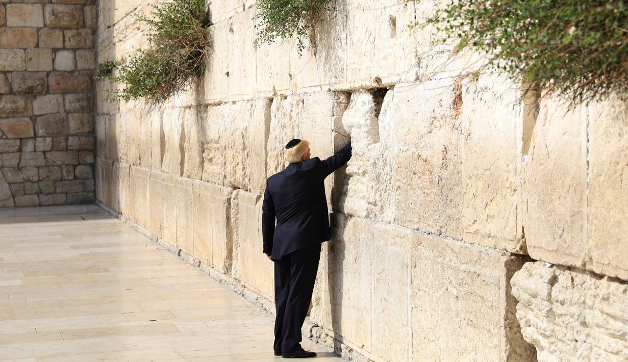 Presiden AS Donald Trump memasukkan sebuah catatan di antara bebatuan Tembok Ratapan, tempat suci milik kaum Yahudi, di Yerusalem, Senin (22/5). Donald Trump menjadi Presiden AS pertama yang berdoa di Tembok Ratapan. (AP Photo/Evan Vucci)