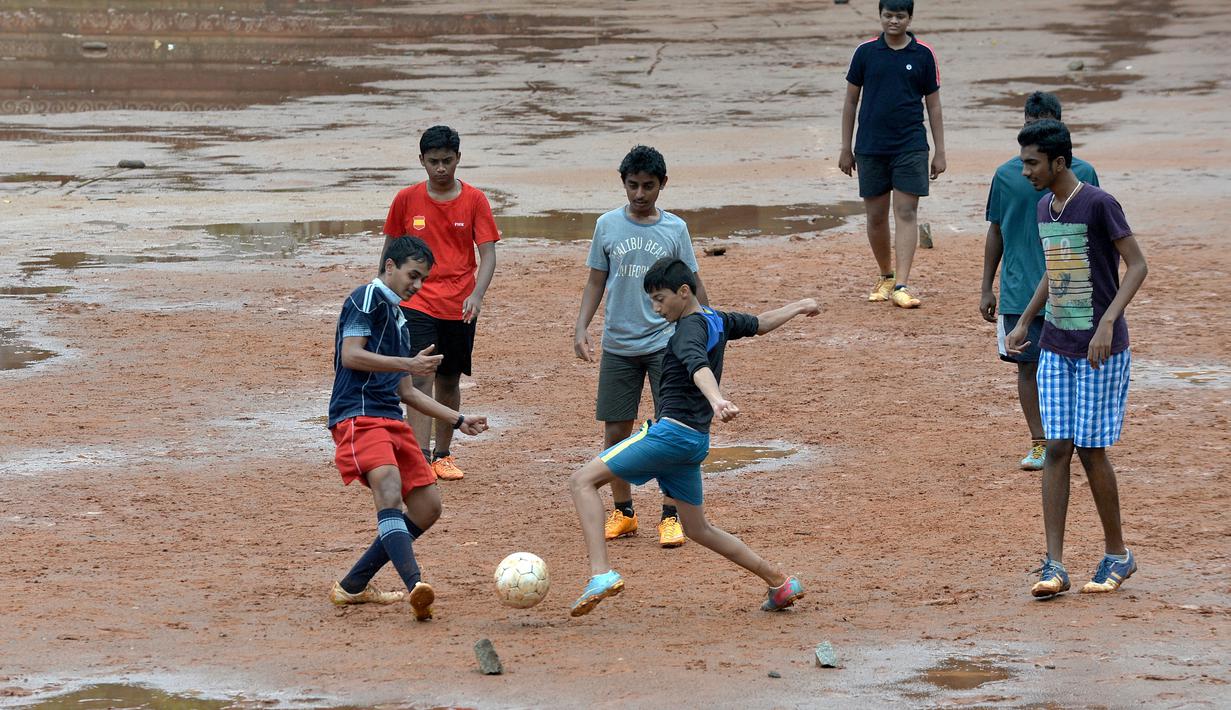 Anak-anak sekolah India bermain bola dekat genangan air di Bangalore, India, Rabu (11/11/2015) WIB.  (AFP Photo/Manjunath Kiran)