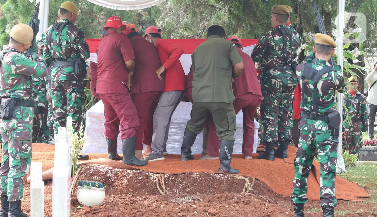 Peti jenazah Almarhum Azyumardi Azra dimasukkan ke dalam liang lahat saat prosesi pemakaman di Taman Makam Pahlawan Kalibata, Jakarta, Selasa (20/9/2022). Prajurit penembak Salvo melepaskan satu kali peluru ke arah udara dilanjutkan alunan pukulan drum mengiringi penurunan peti jenazah ke liang lahat. (Liputan6.com/Herman Zakharia)