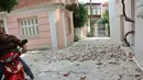 Seorang pria dengan sepeda motor melewati rumah yang rusak setelah gempa bumi di pulau Lesbos, Yunani Timur, Senin (12/6). Sedikitnya 10 orang terluka ketika gempa bumi 6,3 SR mengguncang Laut Aegea di Yunani Timur. (Manolis Lagoutaris/InTime News via AP)