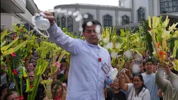 Hari ini, Minggu 29 Maret 2026, juga menandai awal Pekan Suci, peralihan dari masa Prapaskah menuju kisah sengsara, wafat, dan kebangkitan Yesus Kristus. Tampak dalam foto, seorang pekerja gereja memercikkan air suci ke daun palem para umat selama upacara pemberkatan di luar Katedral Antipolo, kota Antipolo, provinsi Rizal, Filipina, saat memperingati Minggu Palma, 29 Maret 2026. (AP Photo/Aaron Favila)
