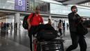 Pelancong dengan membawa barang bawaan mereka berjalan di terminal kedatangan Bandara Internasional Ibukota di Beijing, China, Selasa (14/3/2023). Kementerian negera itu juga mengatakan orang asing pemegang visa yang dikeluarkan sebelum 28 Maret 2020, yang masih dalam masa berlakunya juga akan dapat masuk ke China. (Photo by Jade GAO / AFP)