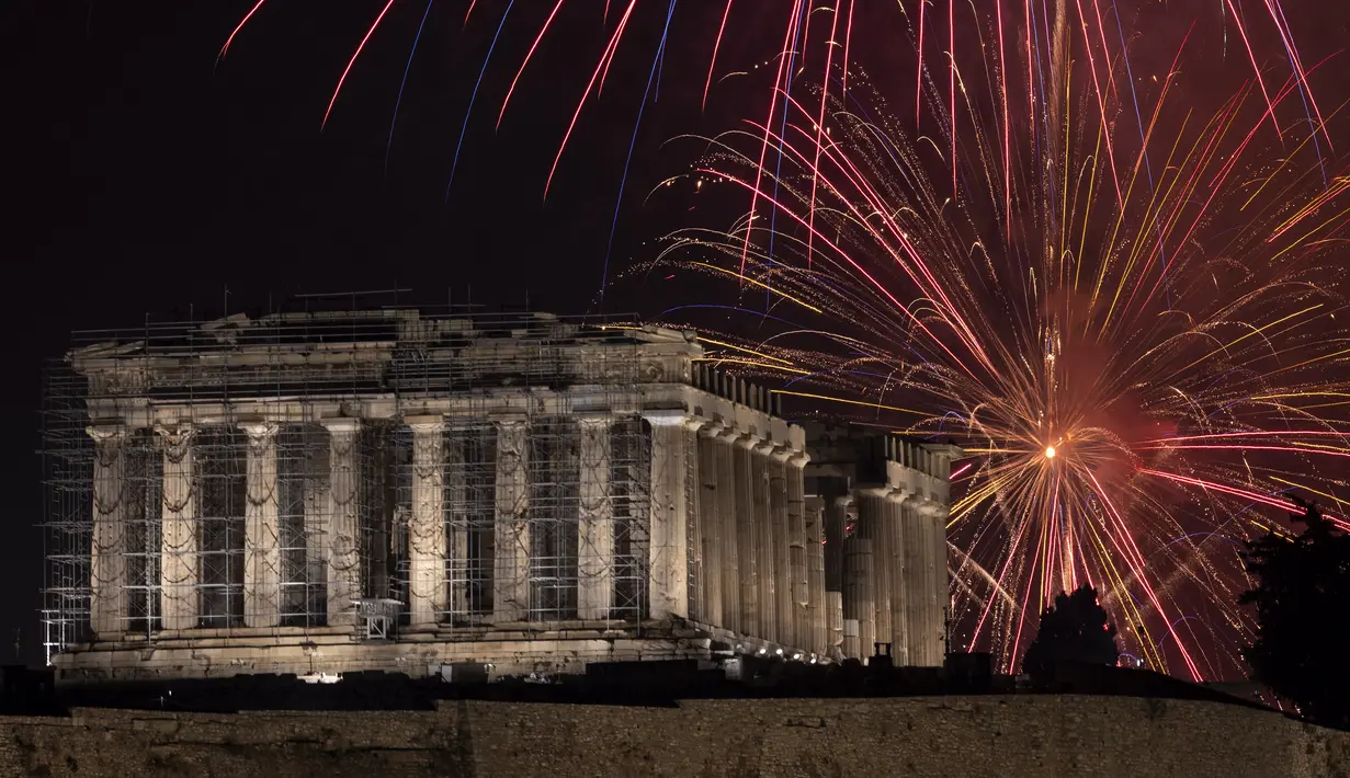Kembang api meledak di atas kuil Parthenon kuno di bukit Acropolis saat perayaan Tahun Baru di Athena, Yunani, Minggu (1/1/2022). Saat pergantian tahun, orang akan beramai-ramai melihat pertunjukan kembang api di langit yang berwarna-warni dan saling bersahutan. (AP Photo/Yorgos Karahalis)