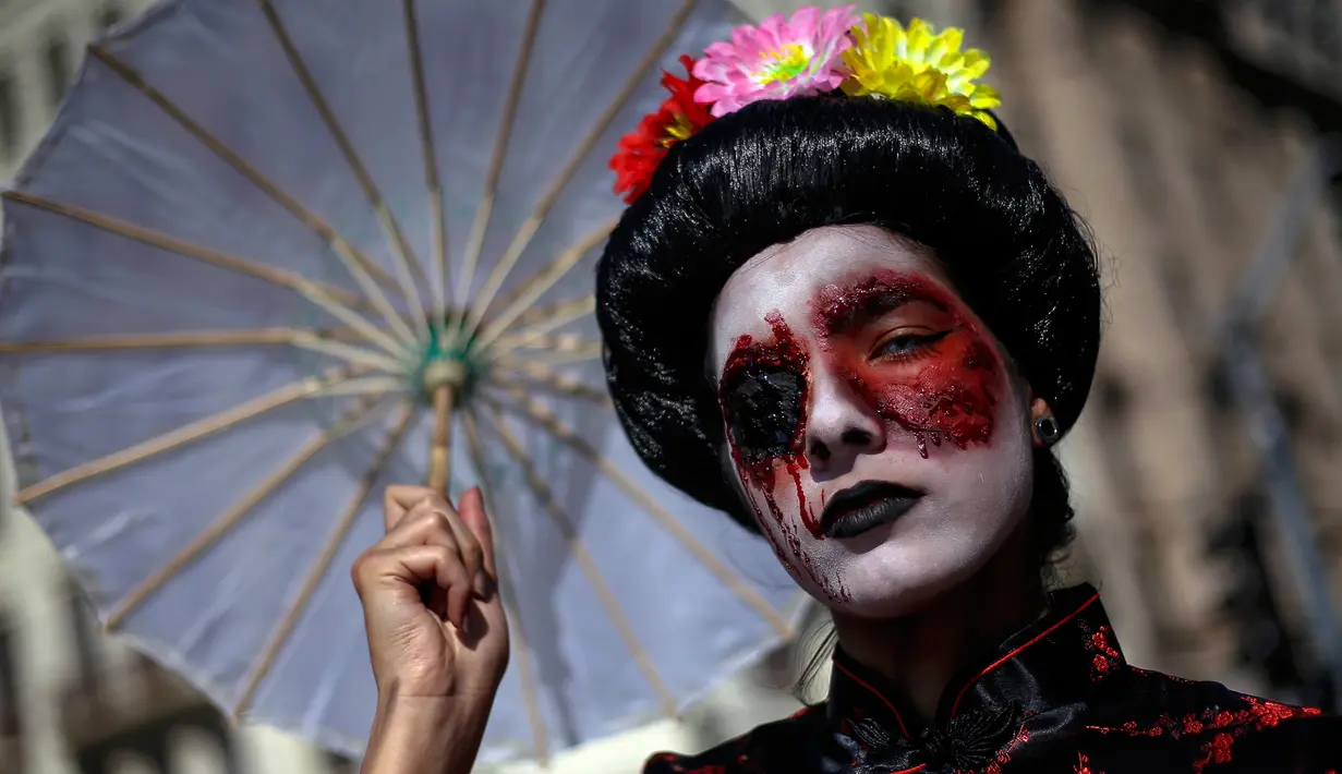 Peserta berpose dengan kostum dan dandanan menyerupai zombie selama acara Zombie Walk di Sao Paulo, Brasil, Sabtu (2/11/2019). Ratusan orang turun ke jalan memakai kostum karakter horor pada acara tahunan yang digelar sejak 2006 pada Hari Para Arwah. (Miguel SCHINCARIOL / AFP)