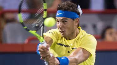 Petenis Spanyol, Rafael Nadal mengembalikan bola ke arah petenis Kanada, Denis Shapovalov pada turnamen Piala Rogers di Montreal, Kamis (10/8). Nadal disingkirkan petenis 18 tahun dengan skor 6-3, 4-6, 6-7. (Paul Chiasson/The Canadian Press via AP)